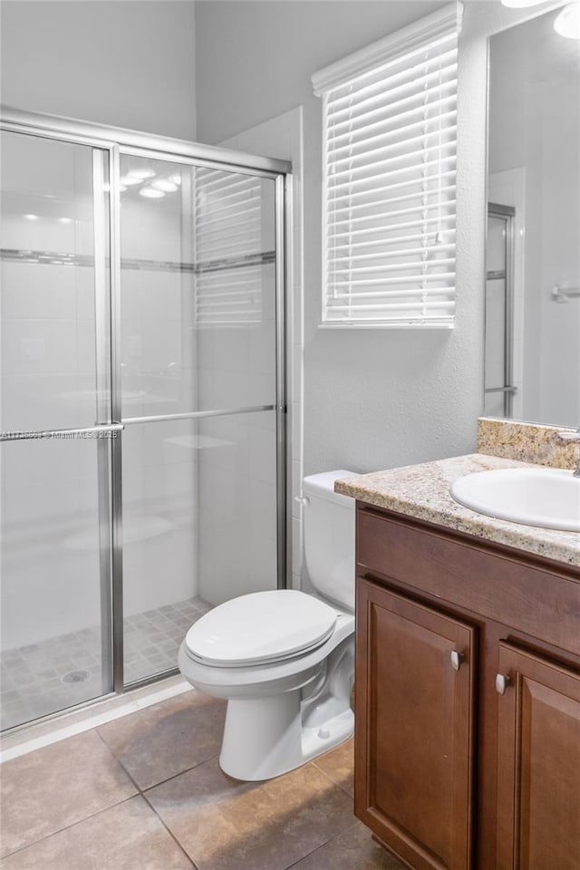 bathroom with walk in shower, tile patterned floors, vanity, and toilet