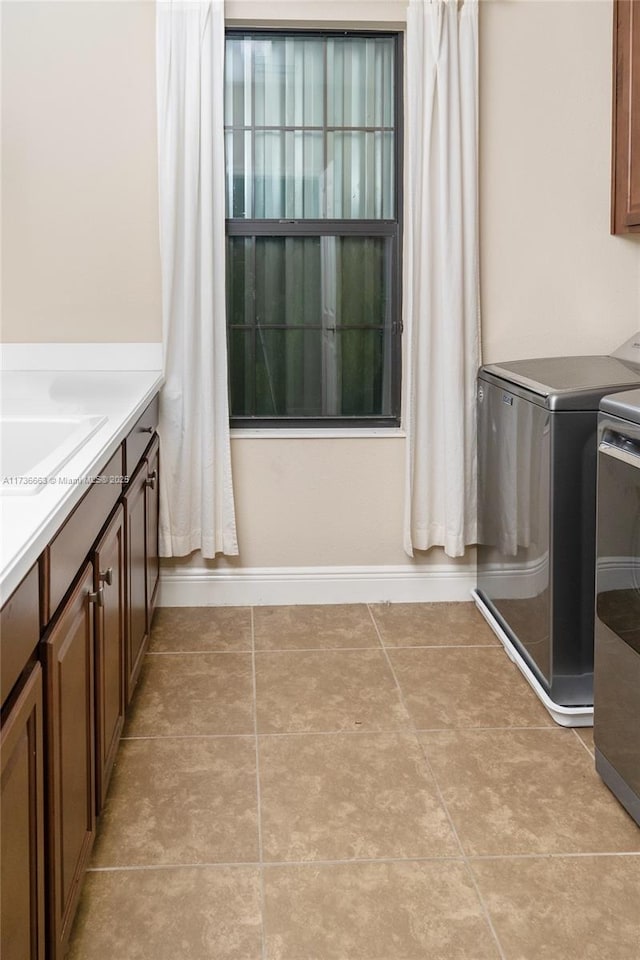 washroom with separate washer and dryer, sink, light tile patterned floors, and cabinets