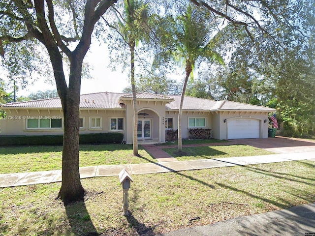 view of front of home featuring french doors, a garage, and a front lawn