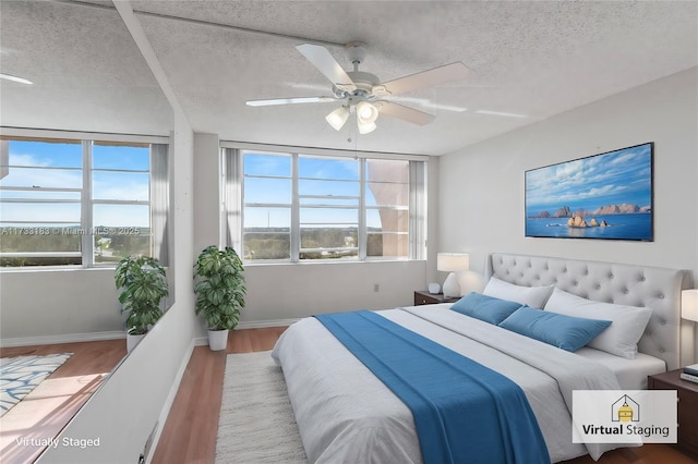 bedroom with multiple windows, wood-type flooring, and a textured ceiling