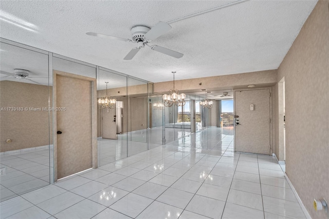 spare room featuring light tile patterned floors, ceiling fan with notable chandelier, and a textured ceiling