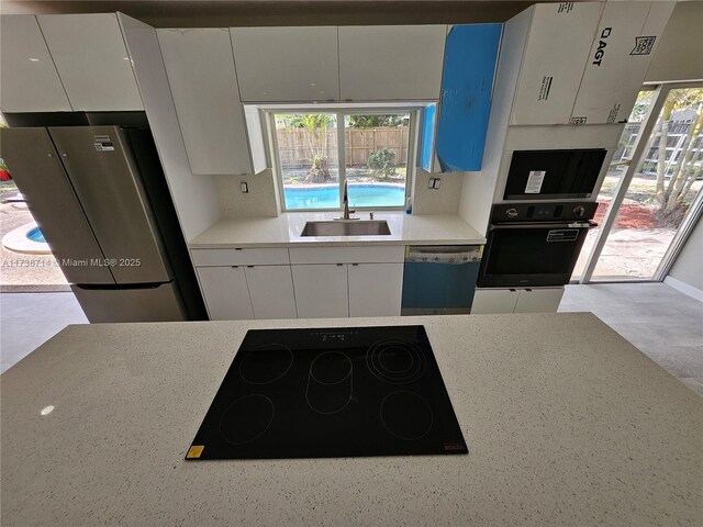 kitchen featuring white cabinetry, sink, plenty of natural light, and black appliances