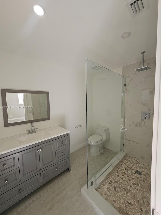 bathroom featuring vanity, toilet, and a tile shower