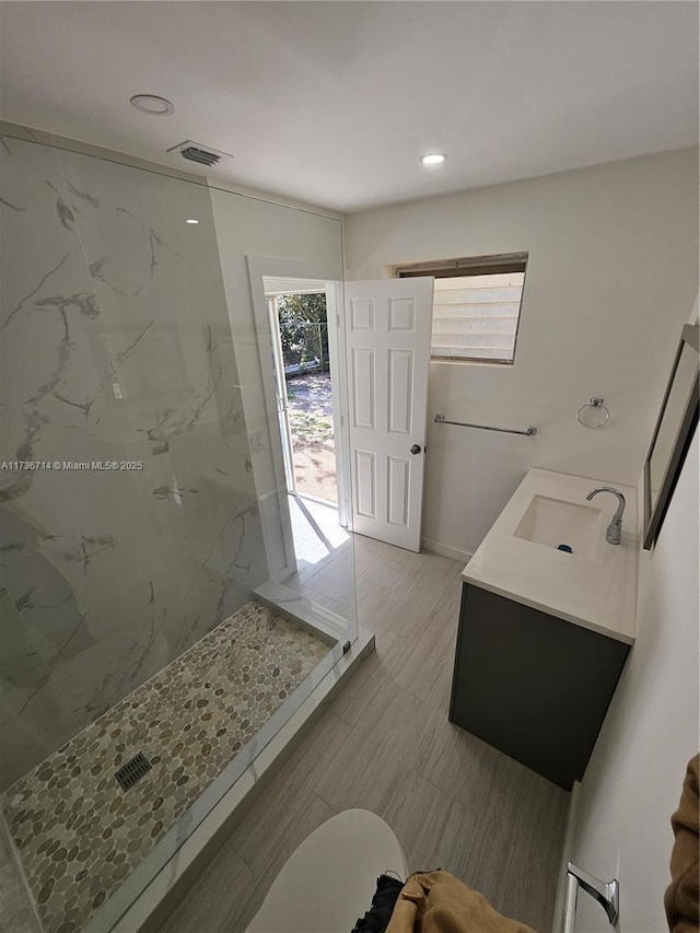 bathroom with tiled shower, vanity, and toilet