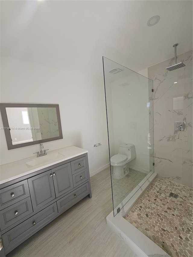 bathroom with vanity, toilet, and a tile shower