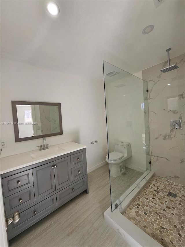 bathroom featuring vanity, toilet, and a tile shower