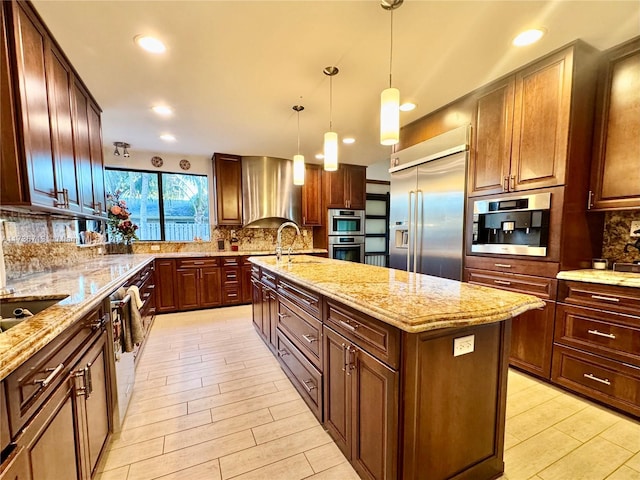 kitchen featuring tasteful backsplash, a kitchen island with sink, wood tiled floor, and stainless steel built in refrigerator