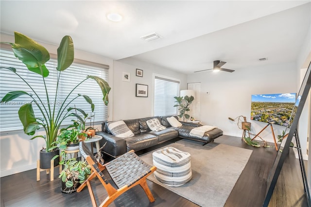 living room with ceiling fan, dark wood-type flooring, visible vents, and baseboards