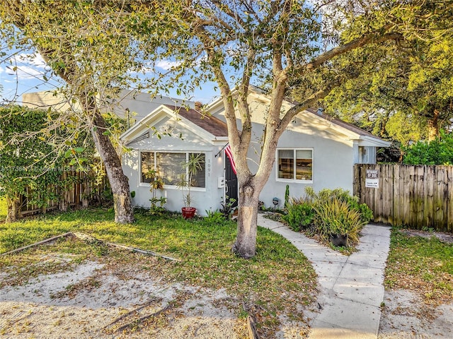 bungalow featuring fence and stucco siding