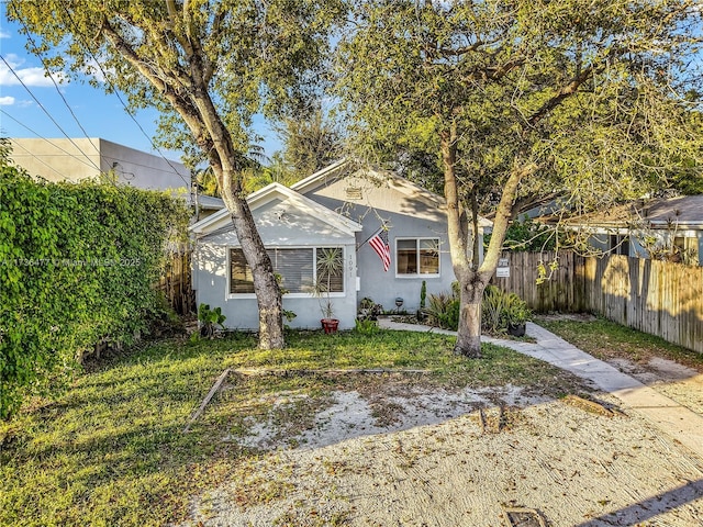 view of front of house featuring fence, a front lawn, and stucco siding