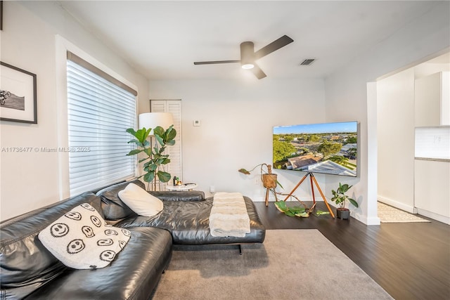 living area featuring ceiling fan, dark wood finished floors, visible vents, and baseboards