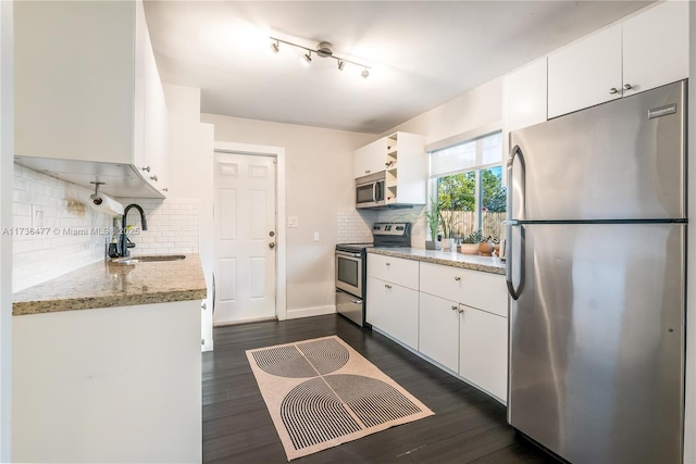 kitchen with sink, white cabinetry, stainless steel appliances, light stone countertops, and dark hardwood / wood-style flooring