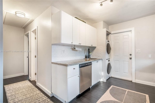 kitchen with tasteful backsplash, white cabinetry, stacked washer / drying machine, stainless steel dishwasher, and dark wood-type flooring