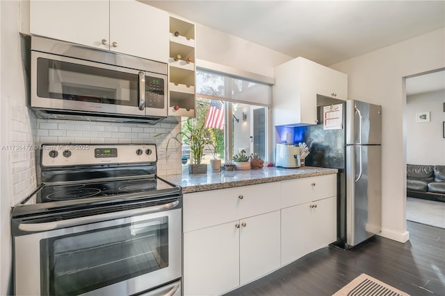 kitchen with stainless steel appliances, white cabinetry, tasteful backsplash, and light stone counters