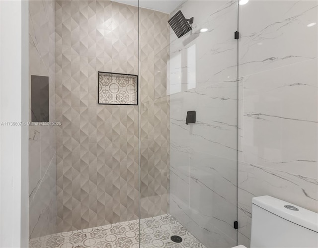 bathroom featuring a shower with shower door and toilet