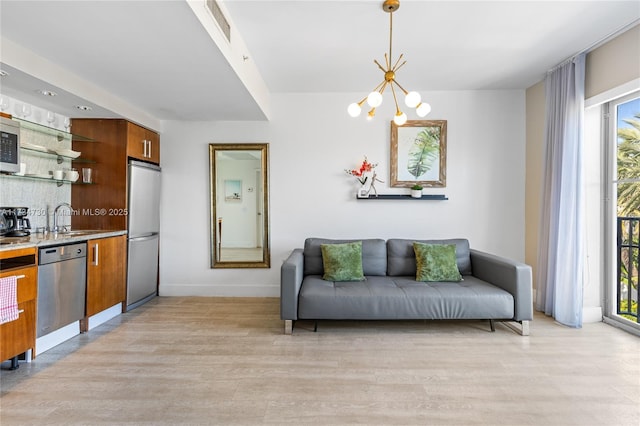 living room with a chandelier, sink, and light hardwood / wood-style flooring