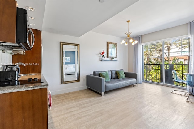 interior space featuring sink, an inviting chandelier, hanging light fixtures, light hardwood / wood-style flooring, and light stone countertops