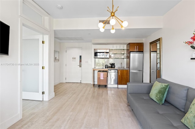 living room featuring sink, an inviting chandelier, and light hardwood / wood-style flooring