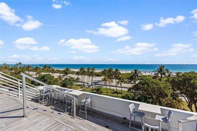 wooden deck featuring a water view, a beach view, and an outdoor bar