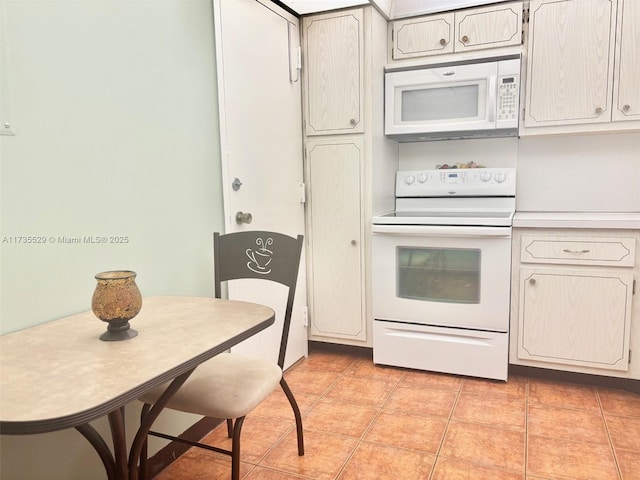 kitchen featuring light tile patterned flooring, white appliances, and white cabinets