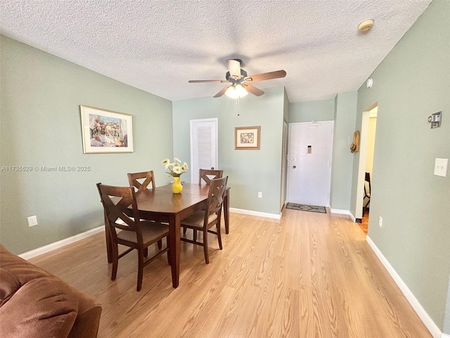 dining space with ceiling fan, a textured ceiling, and light wood-type flooring