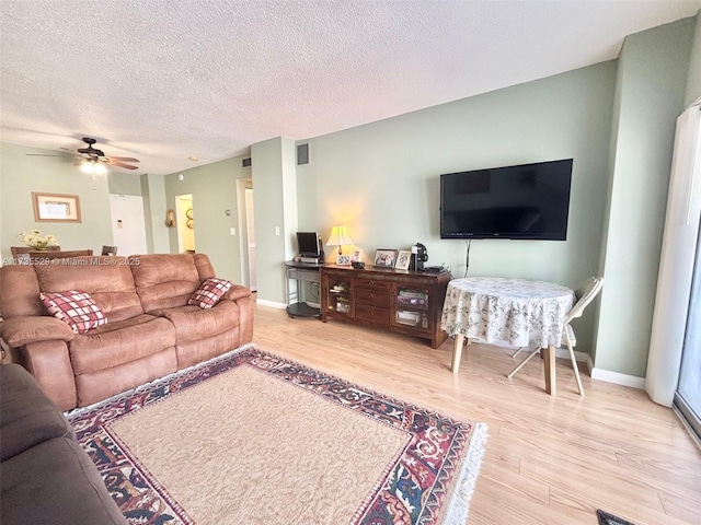 living room featuring ceiling fan, a textured ceiling, and light hardwood / wood-style floors