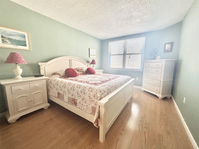 bedroom featuring light hardwood / wood-style floors and a textured ceiling