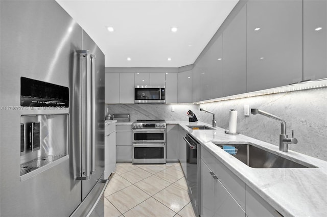 kitchen with sink, backsplash, gray cabinets, and stainless steel appliances