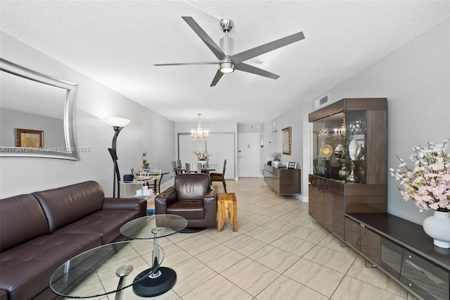 living room featuring ceiling fan with notable chandelier, a textured ceiling, and light tile patterned floors