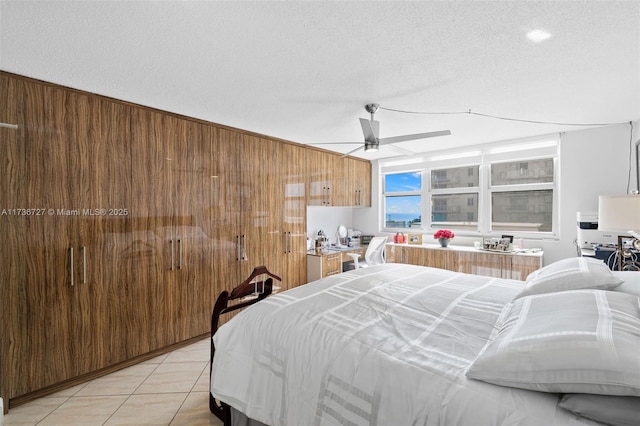 bedroom with light tile patterned floors, wooden walls, a textured ceiling, and ceiling fan