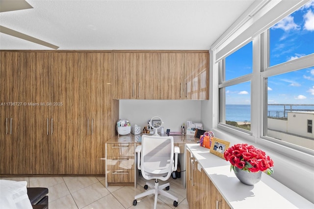 tiled office space featuring wooden walls, a textured ceiling, and a water view