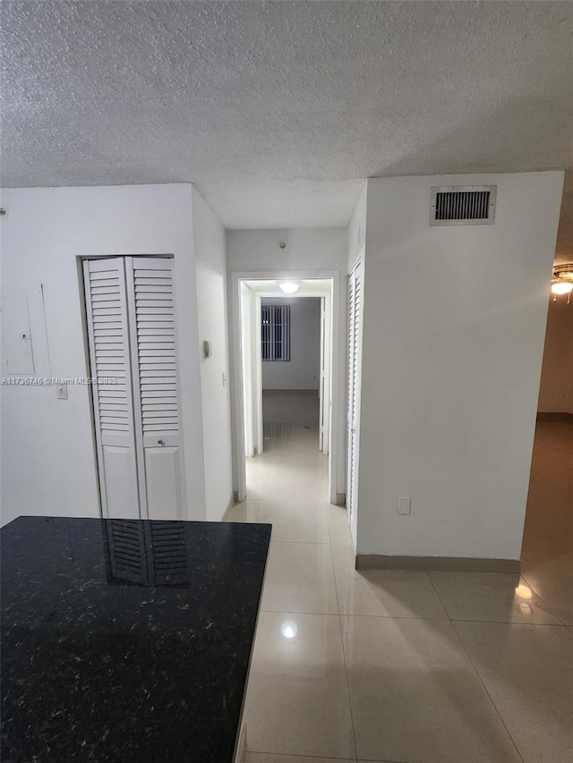 hall featuring light tile patterned flooring and a textured ceiling