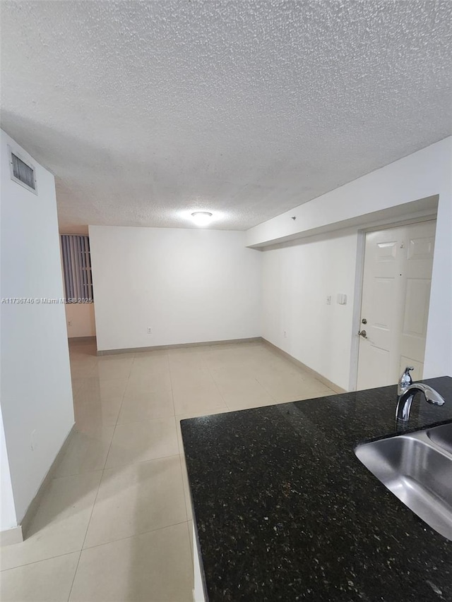 tiled spare room featuring sink and a textured ceiling