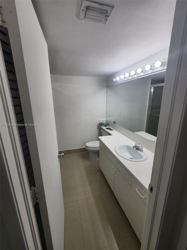 bathroom featuring vanity, toilet, a shower with shower door, and tile patterned flooring