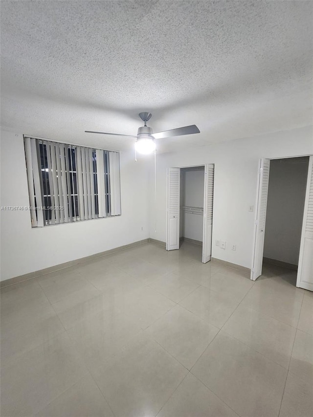 unfurnished bedroom with ceiling fan, a textured ceiling, and light tile patterned floors