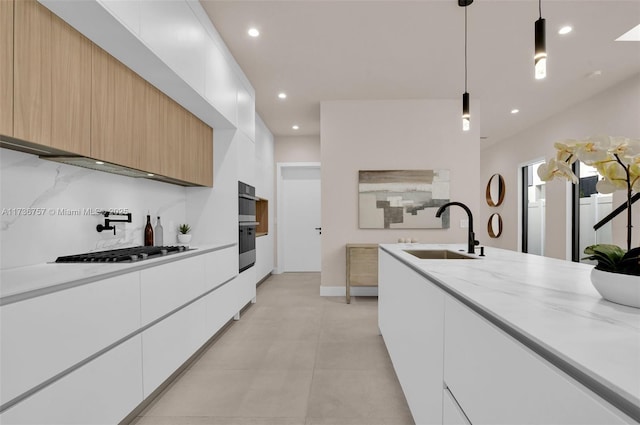 kitchen featuring sink, white cabinetry, hanging light fixtures, light stone countertops, and stainless steel gas stovetop