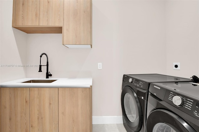 clothes washing area featuring washer and dryer, sink, and cabinets