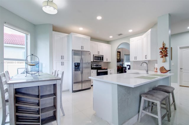 kitchen with sink, white cabinetry, tasteful backsplash, appliances with stainless steel finishes, and kitchen peninsula