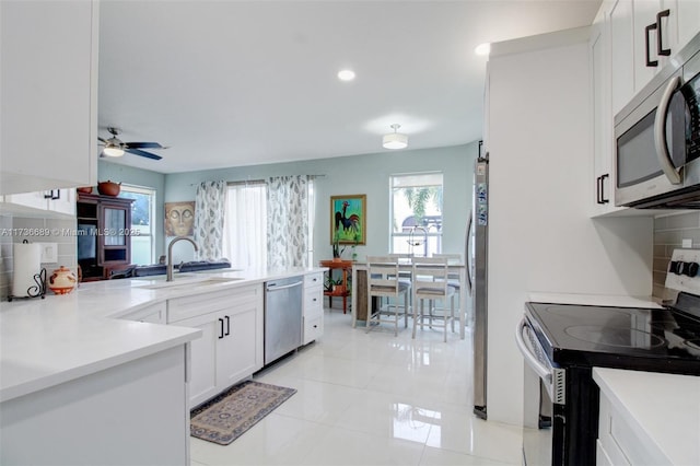 kitchen featuring sink, appliances with stainless steel finishes, white cabinetry, decorative backsplash, and kitchen peninsula