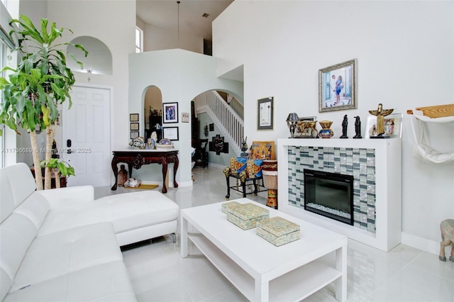 living room featuring a tiled fireplace, a high ceiling, and light tile patterned floors