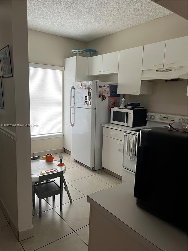 kitchen featuring a textured ceiling, white cabinets, white appliances, and light tile patterned floors