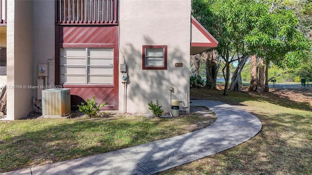 view of exterior entry featuring central AC unit and a yard