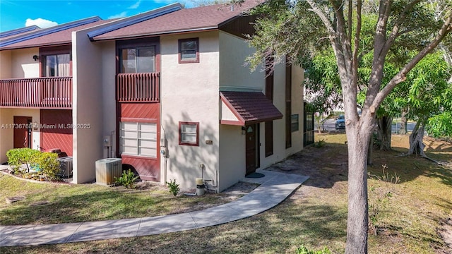 view of side of property with central AC, a balcony, and a yard