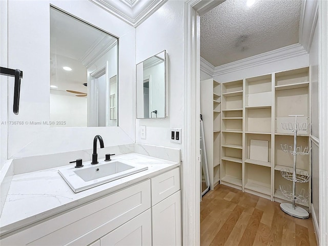 bathroom with vanity, hardwood / wood-style floors, crown molding, and a textured ceiling