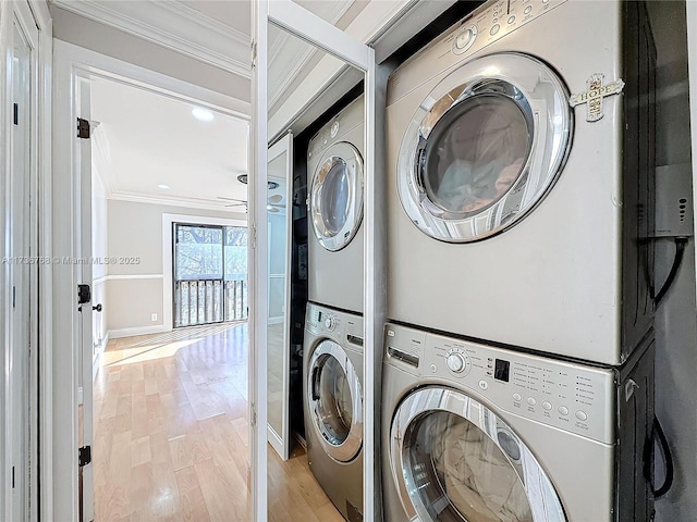 laundry area featuring crown molding, stacked washer and clothes dryer, and light wood-type flooring