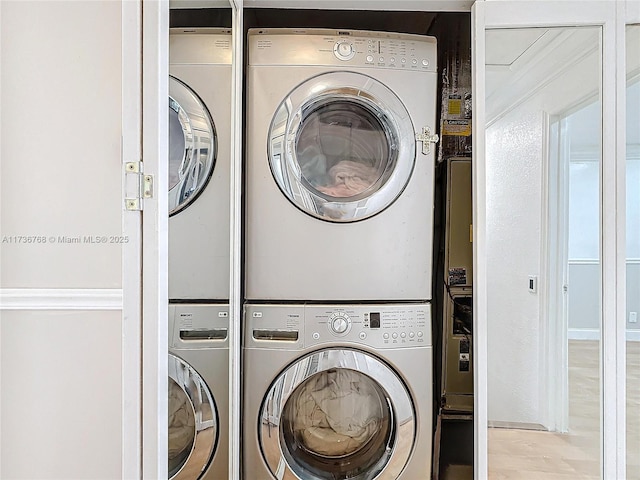 clothes washing area with light hardwood / wood-style floors and stacked washer / dryer