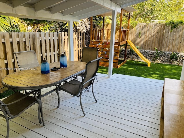 wooden terrace featuring a playground and a lawn