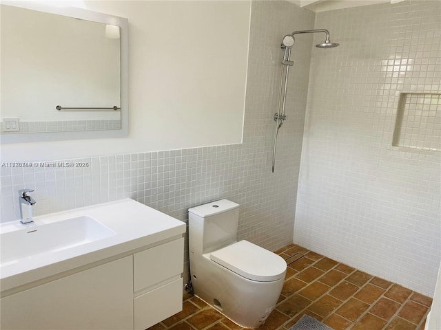 bathroom with vanity, tiled shower, tile walls, and toilet