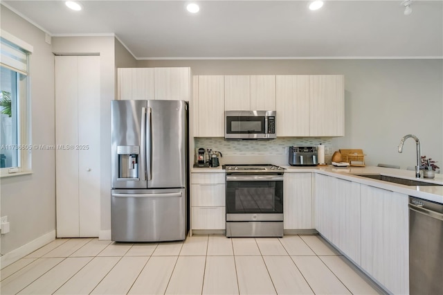 kitchen featuring sink, crown molding, light tile patterned floors, appliances with stainless steel finishes, and tasteful backsplash