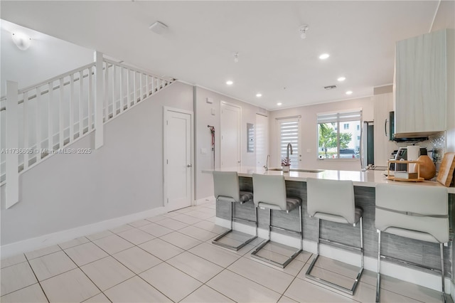 kitchen featuring sink, stainless steel fridge, a kitchen breakfast bar, light tile patterned flooring, and kitchen peninsula